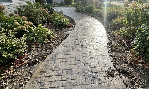 A decorative stamped concrete walkway designed to look like real cobblestone stones.