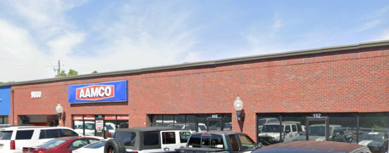 AMCO auto service building with parked cars in front under a cloudy sky