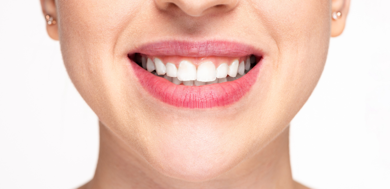 A close up of a woman 's mouth with white teeth and red lips.