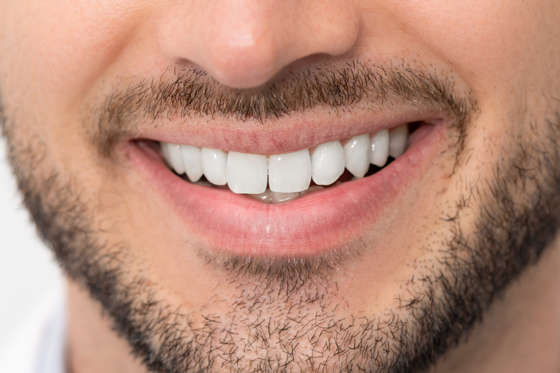 A close up of a man 's mouth with a beard and white teeth.