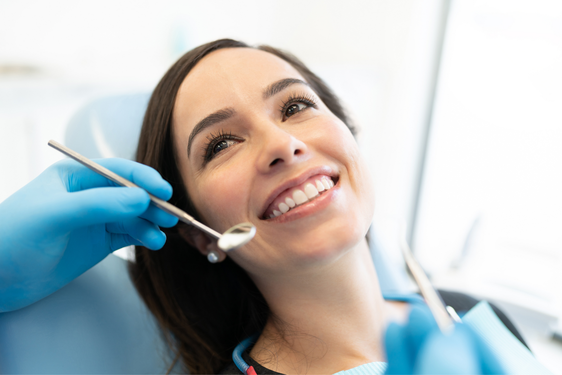 A woman is smiling while having her teeth examined by a dentist.