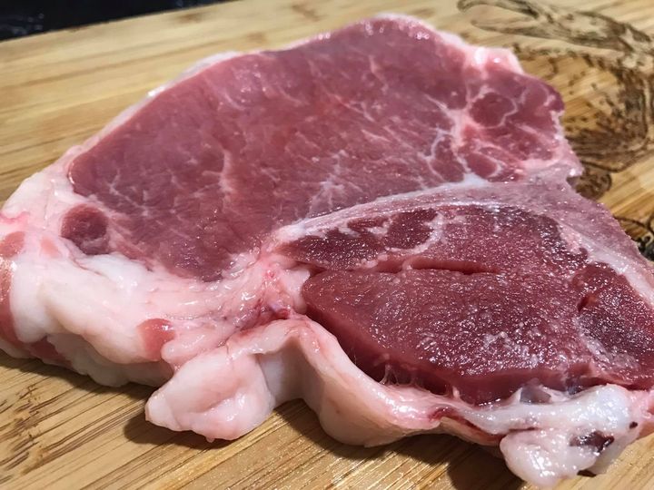Raw pork chop on a wooden cutting board