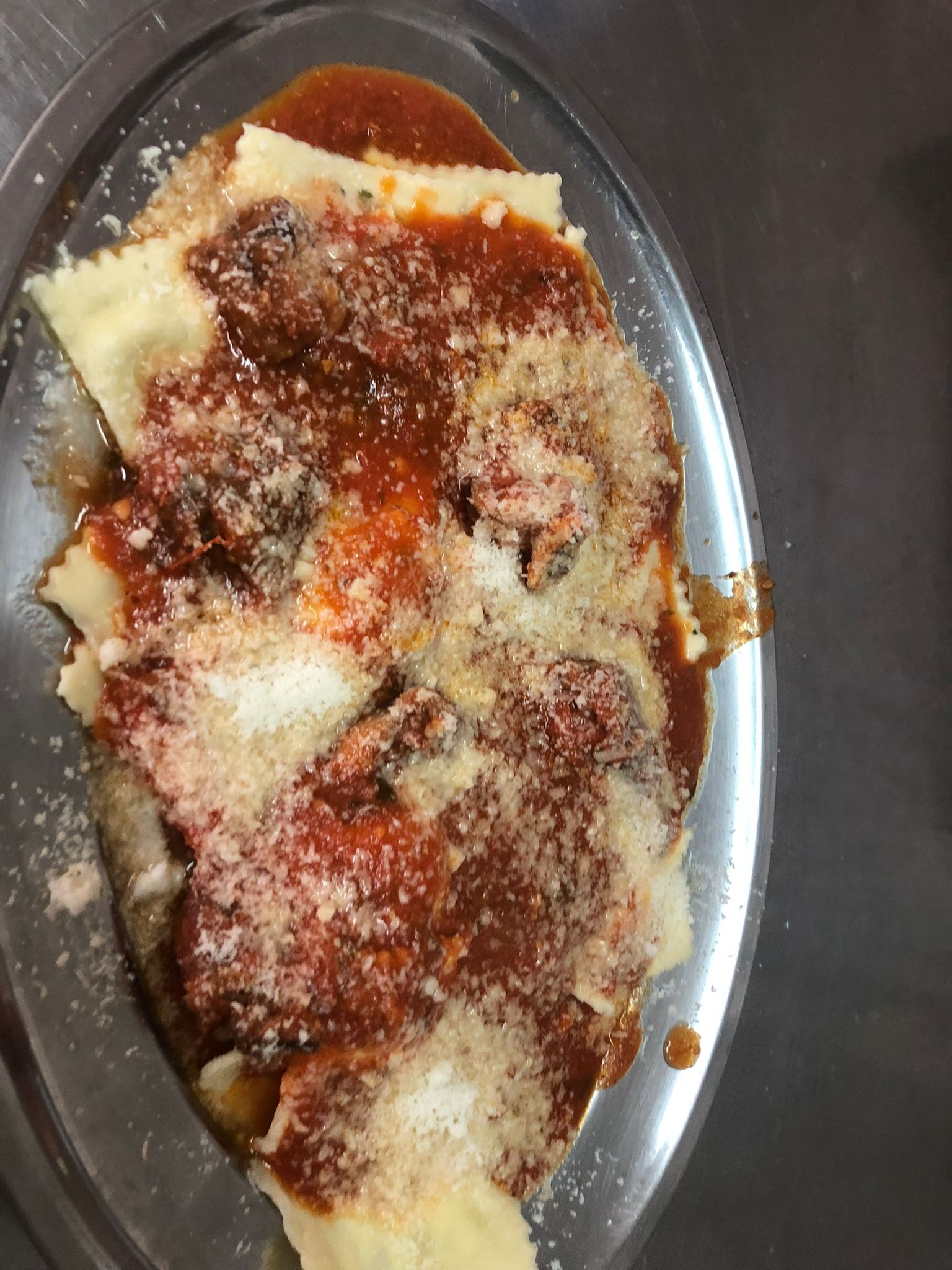 Piatto ovale con un dessert in polvere ricoperto di salsa rossa e cannella spolverata.