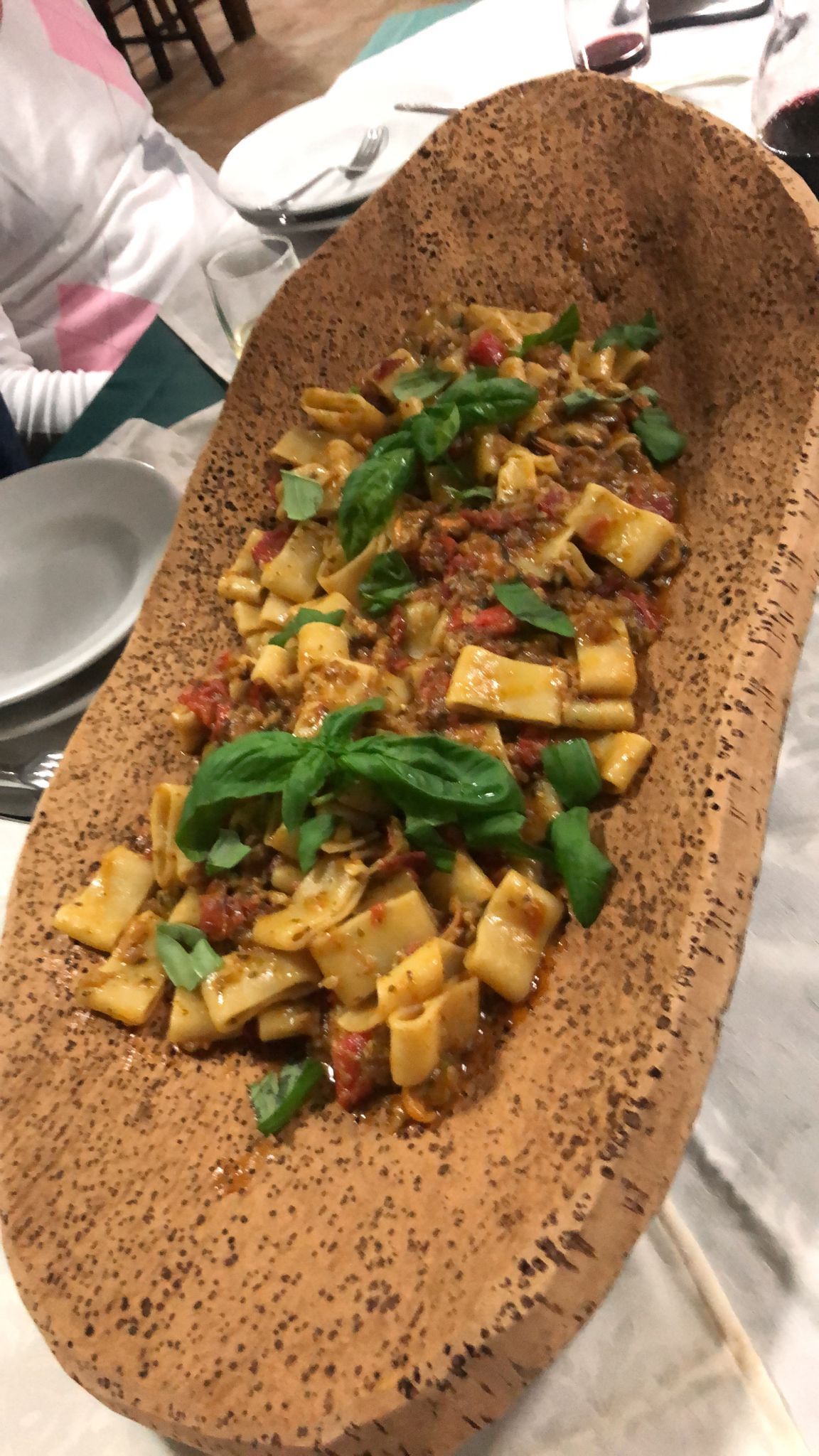 Piatto ovale allungato con cibo a cubetti e guarnizione di basilico, servito su un tavolo.