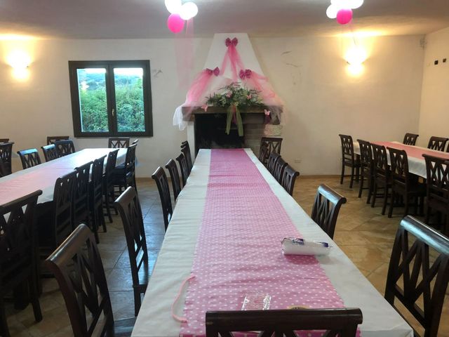 Sala per banchetti decorata con un lungo runner rosa da tavola e un baldacchino floreale in fondo.