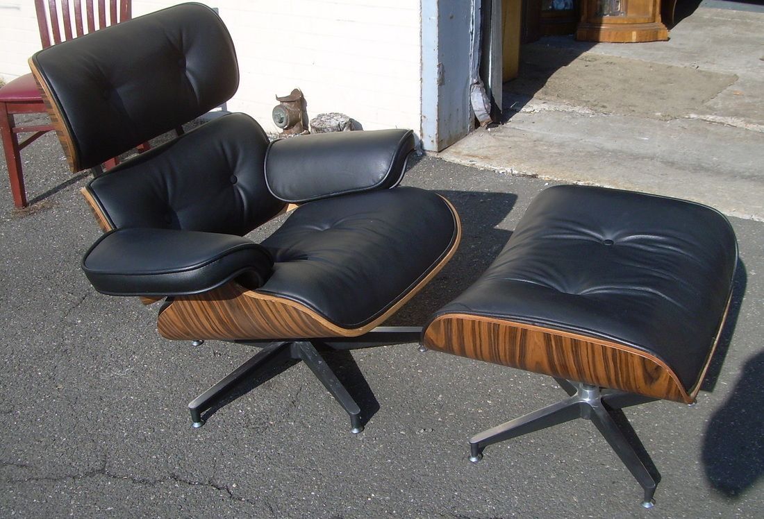 Black leather lounge chair with matching ottoman on a concrete floor outdoors