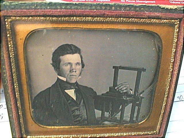 Framed vintage portrait of a man seated beside a chair, in sepia tones