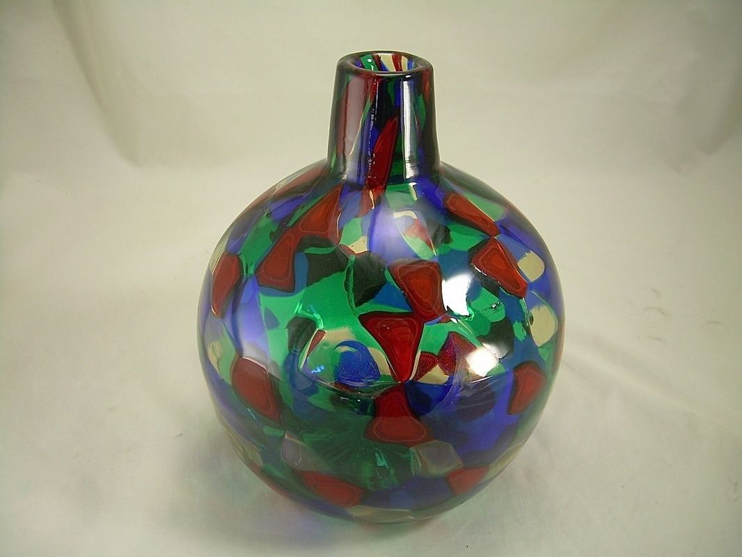 Colorful abstract glass vase with a narrow neck on a plain light background