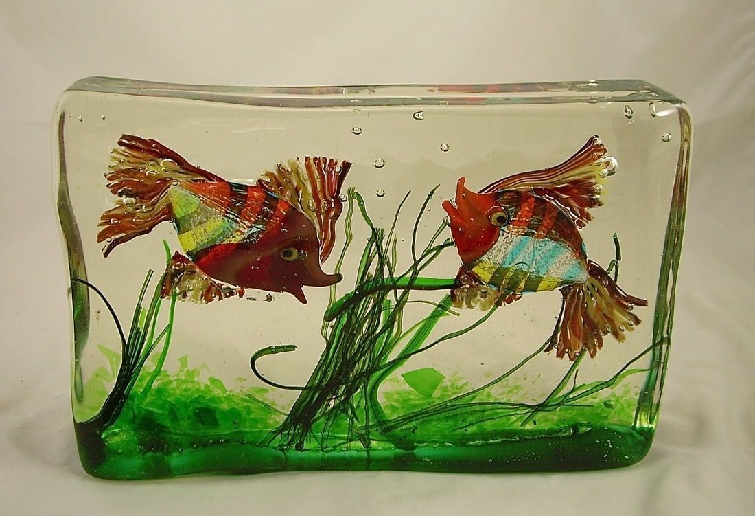 Two colorful fish painted on a small glass block with green aquatic plants and a white background
