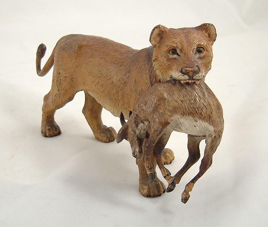 Small brown lion statue holding a deer in its mouth on a white background