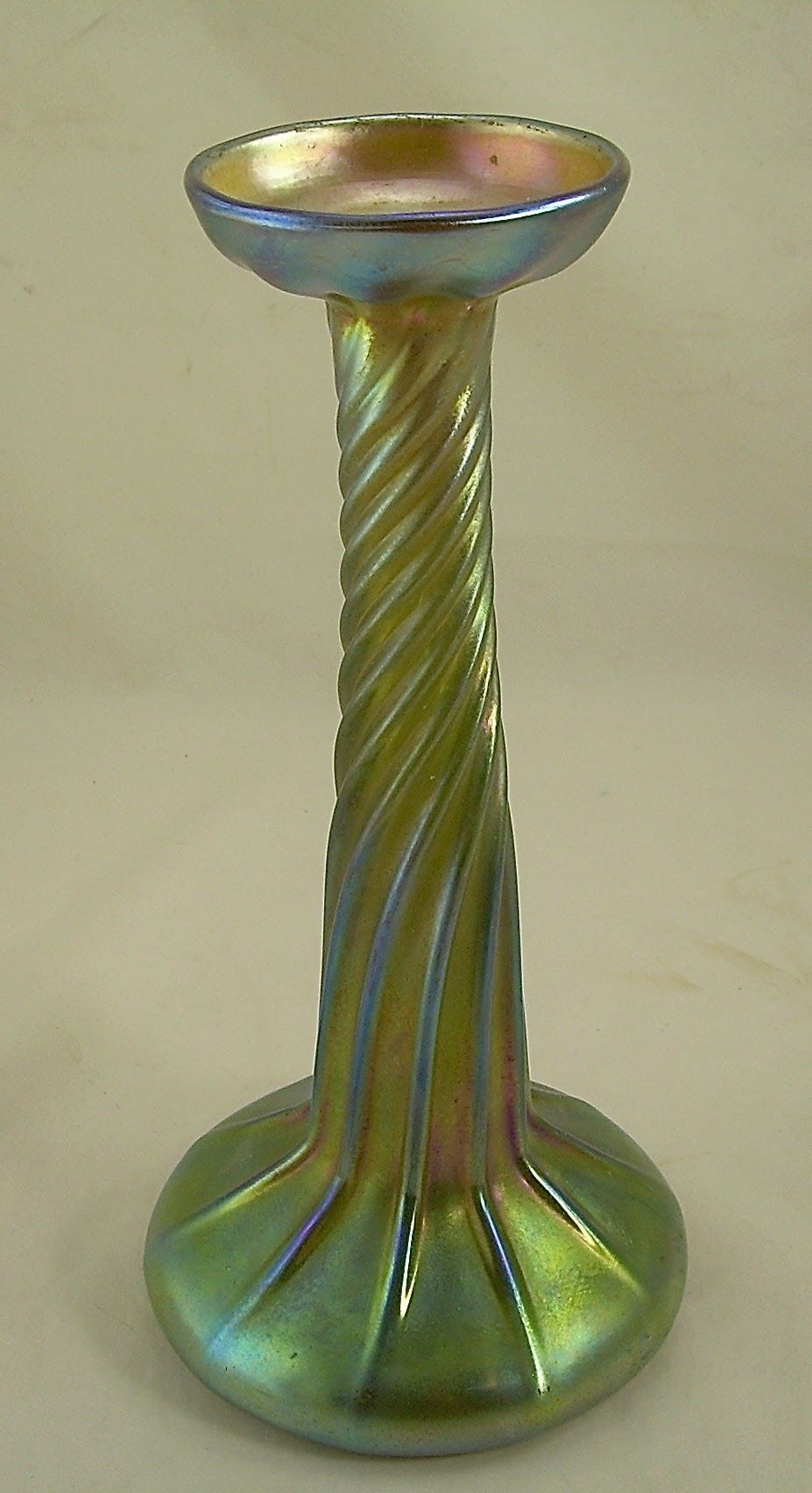 Green iridescent twisted glass candlestick holder with a flared top and round base