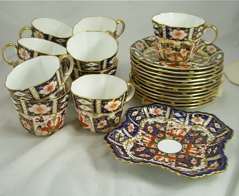 Assorted ornate teacups and saucers stacked on a white background