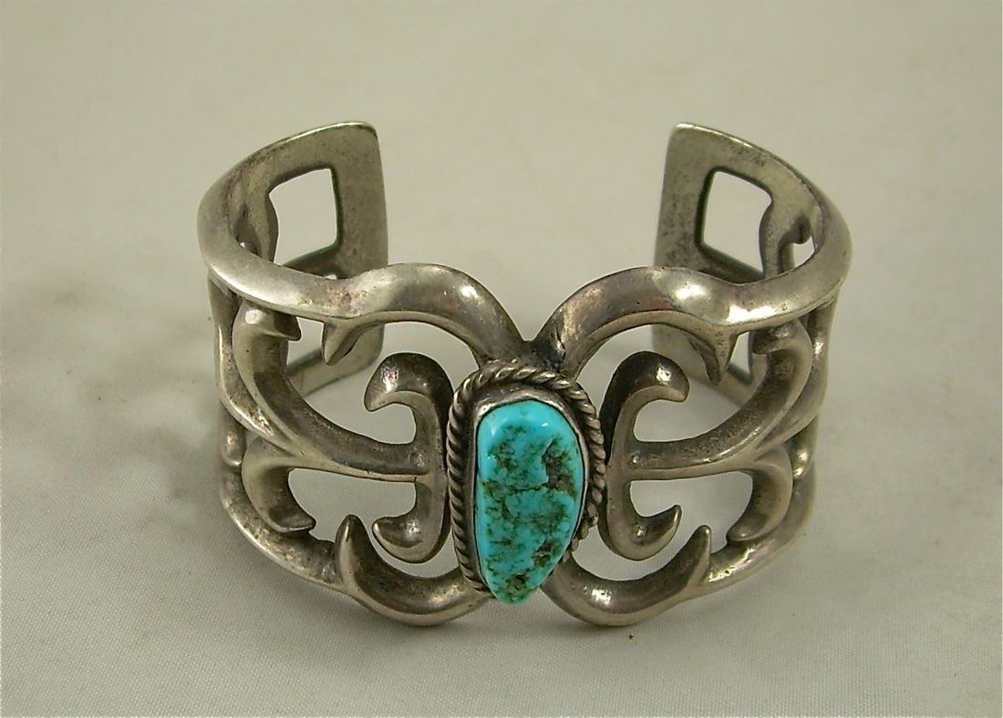 Silver ring with an ornate openwork design and a turquoise stone centerpiece