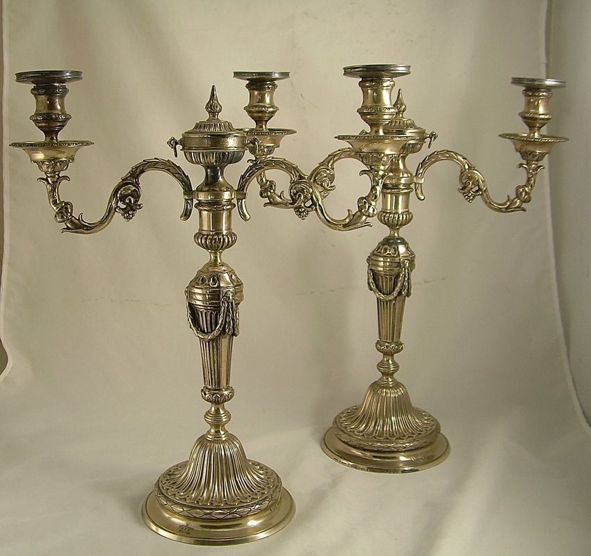 Pair of ornate brass candelabra with five candle holders each, on a plain background