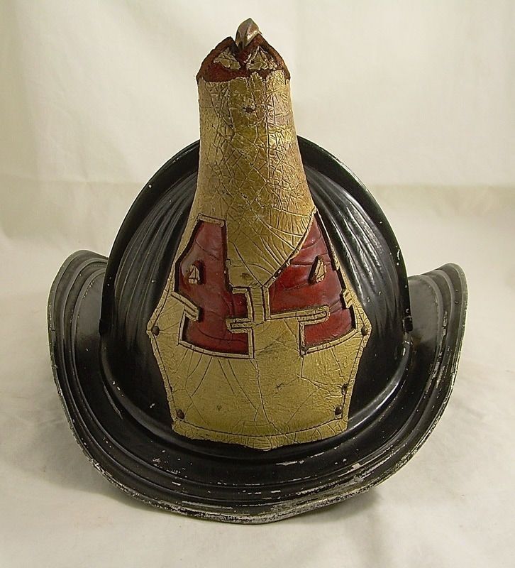 Red and gold vintage firefighter helmet with a black brim on a plain light background