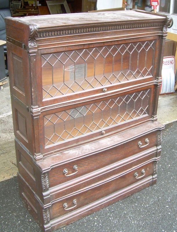 Dark wooden hutch with glass-front doors and two lower drawers on a pavement.