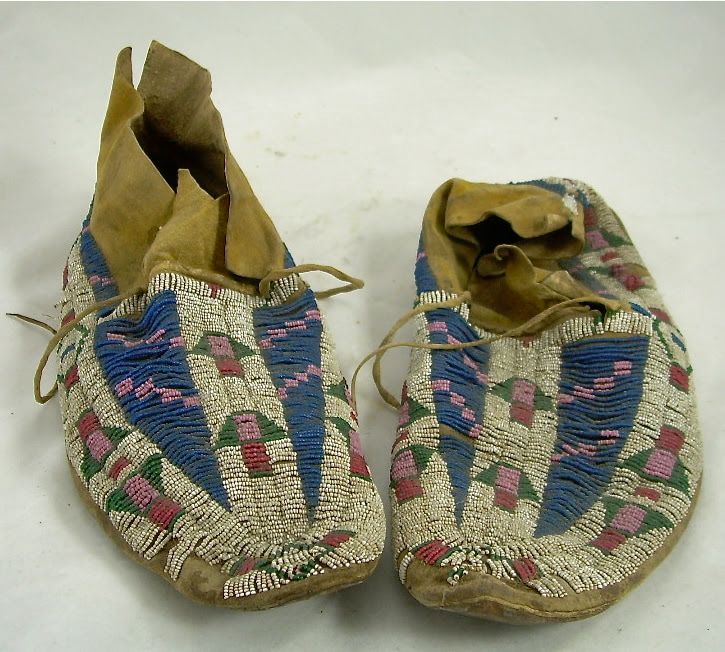 Pair of beaded moccasins with tan leather and blue, pink, and white geometric patterns.