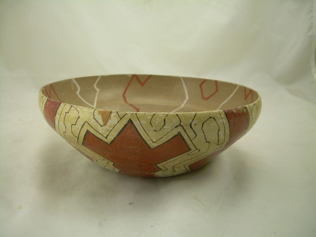 Decorative ceramic bowl with geometric red, cream, and brown patterns on a white background