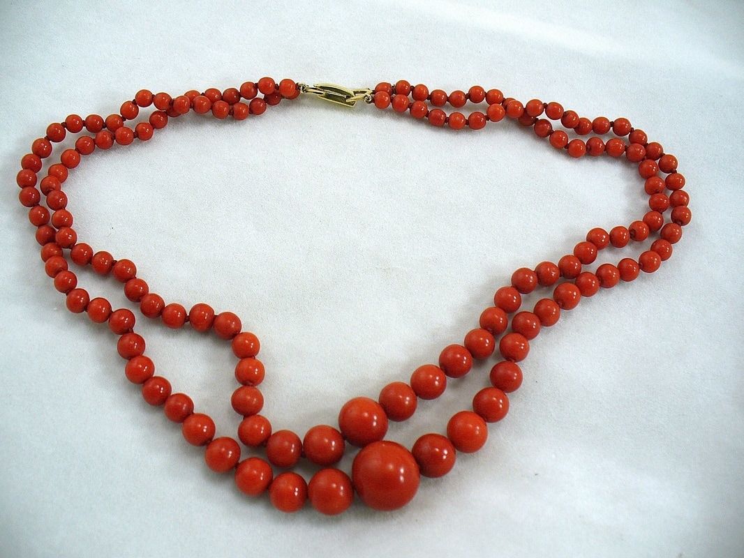 Red beaded necklace laid out in a loop on a white background