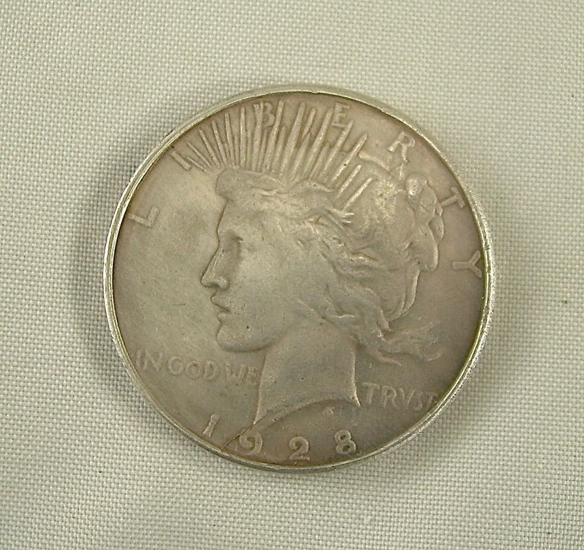Close-up of a worn 1923 Peace silver dollar coin on fabric.