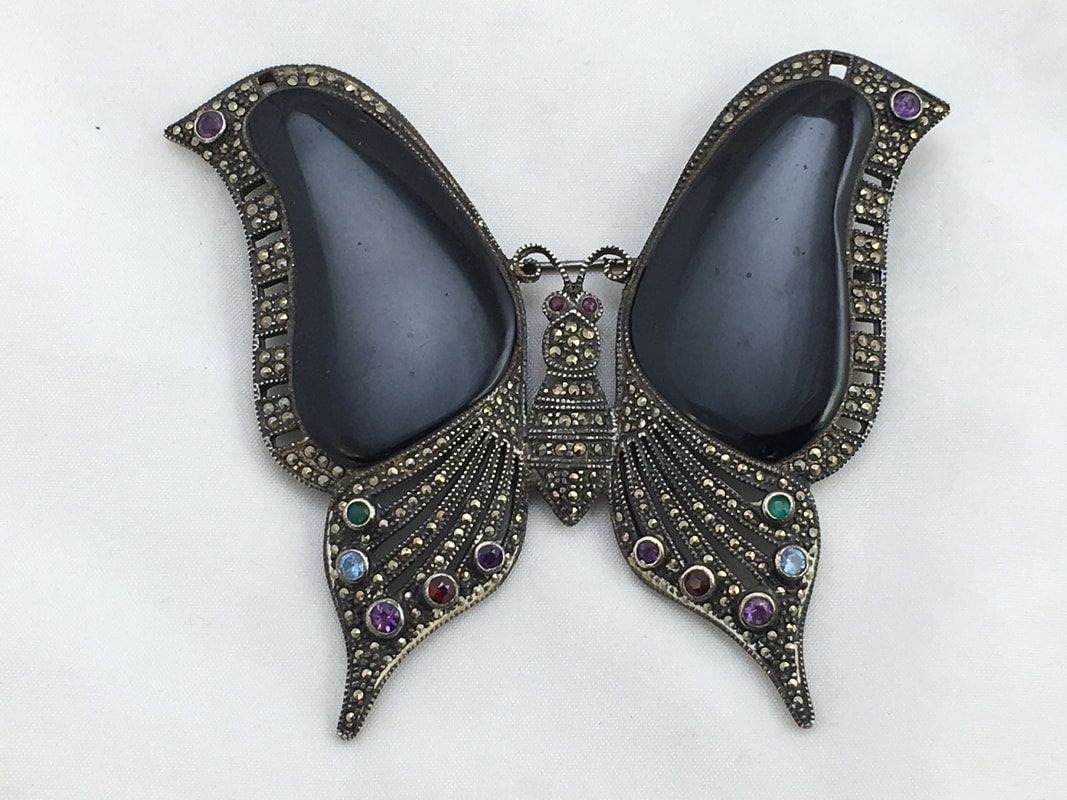 Black butterfly brooch with jeweled wings and iridescent accents