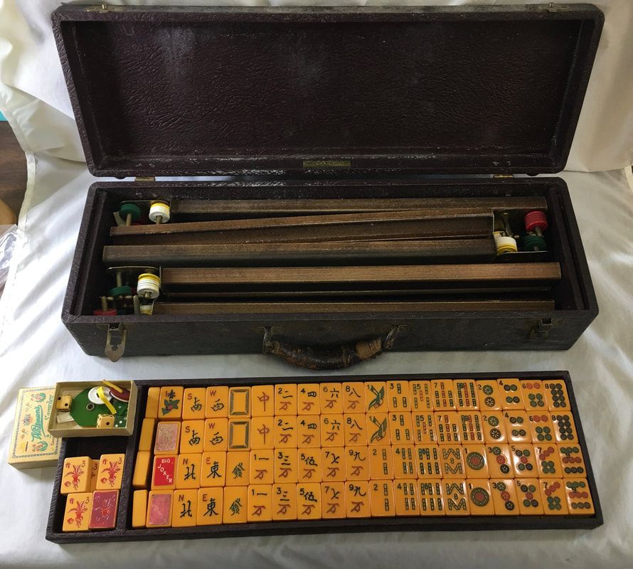 Open black case with two long rods and a small yellow-orange game board with tiles laid out beside it