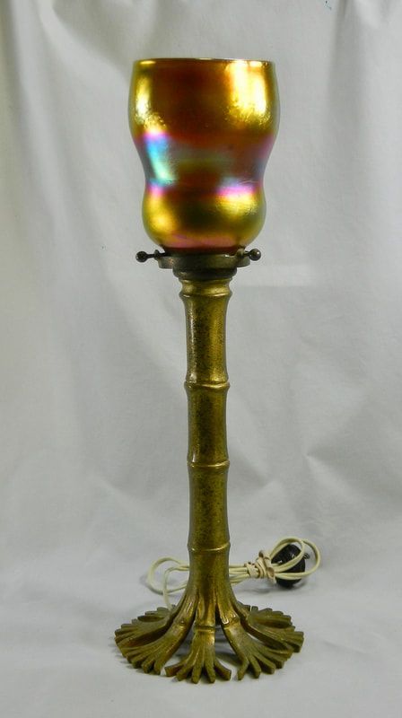 Golden iridescent goblet-style lamp with a bamboo stem and ornate base on a light background