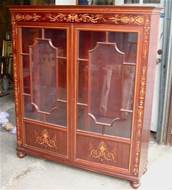 Ornate reddish-brown wooden display cabinet with glass doors and gold decorative trim