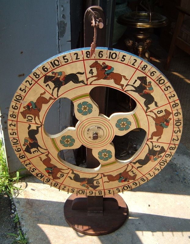 Vintage numbered wheel game on a stand, painted in beige, red, green, and black.