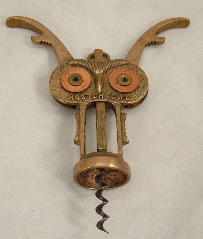 Brass owl-shaped corkscrew with orange eyes and spiral screw, shown on a plain background