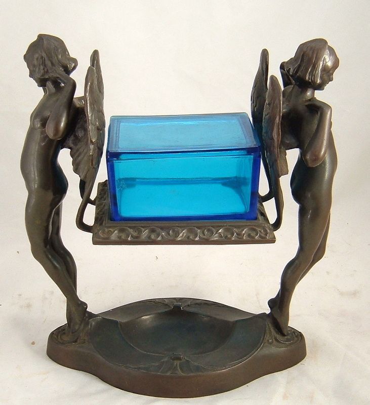 Decorative bronze-toned figurine holding a blue glass box on a round base
