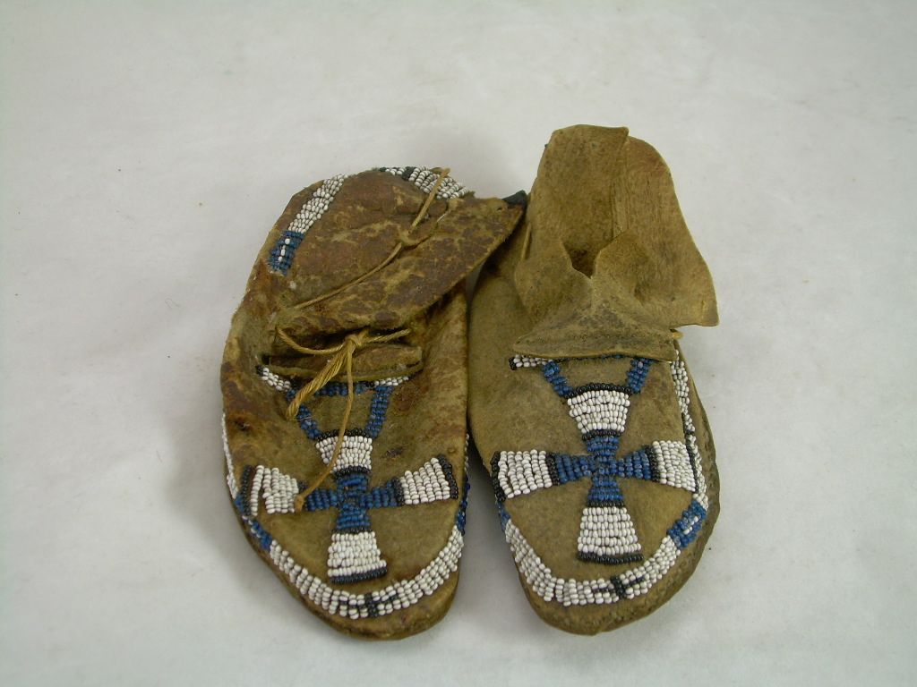 Pair of worn sandals with blue-and-white woven straps on a light background