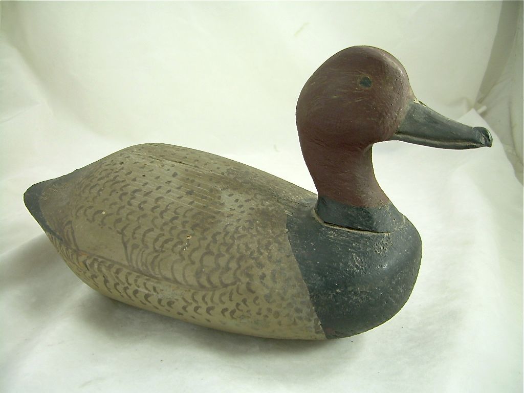 Carved duck decoy with brown body and dark head, facing right on a white background