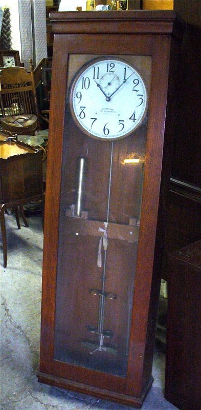 Wooden grandfather clock with glass door and white clock face indoors