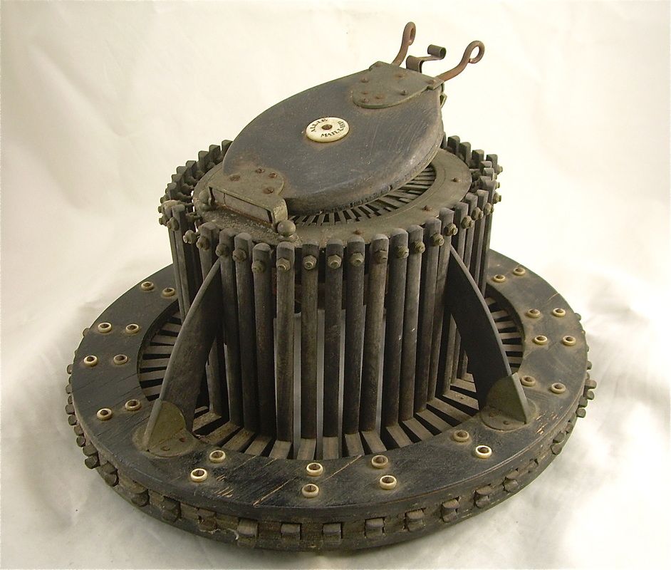 Old mechanical turbine-like device with a circular base and vertical metal rods, shown against a plain background