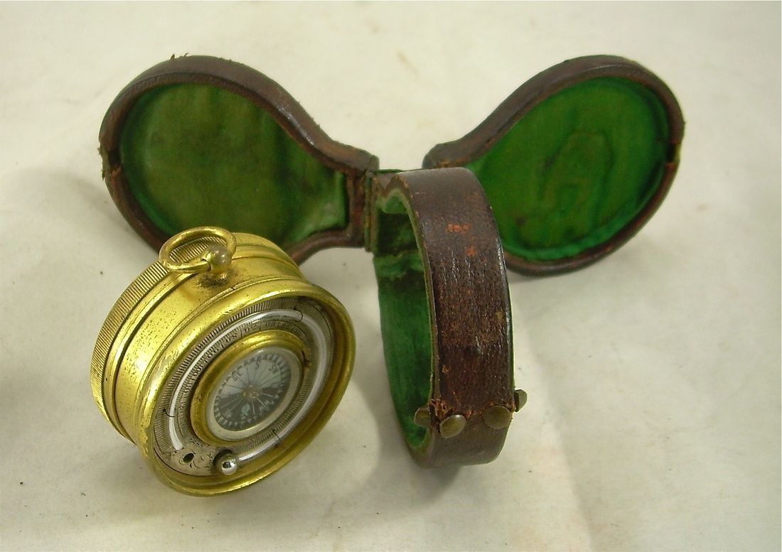Vintage brass pocket watch open with green-lined case and detached watch face.
