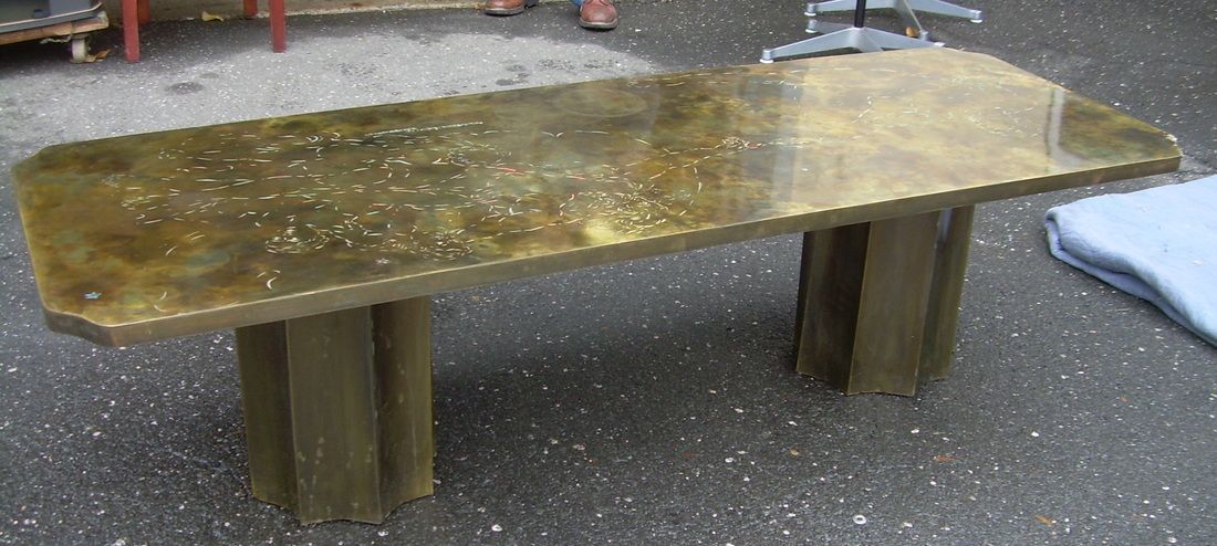 Weathered wooden picnic table on gravel with dark, stained legs