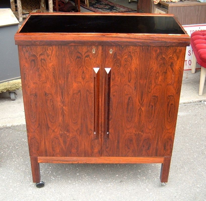 Wood-grain cabinet with open top and two front doors on short legs, standing outdoors.
