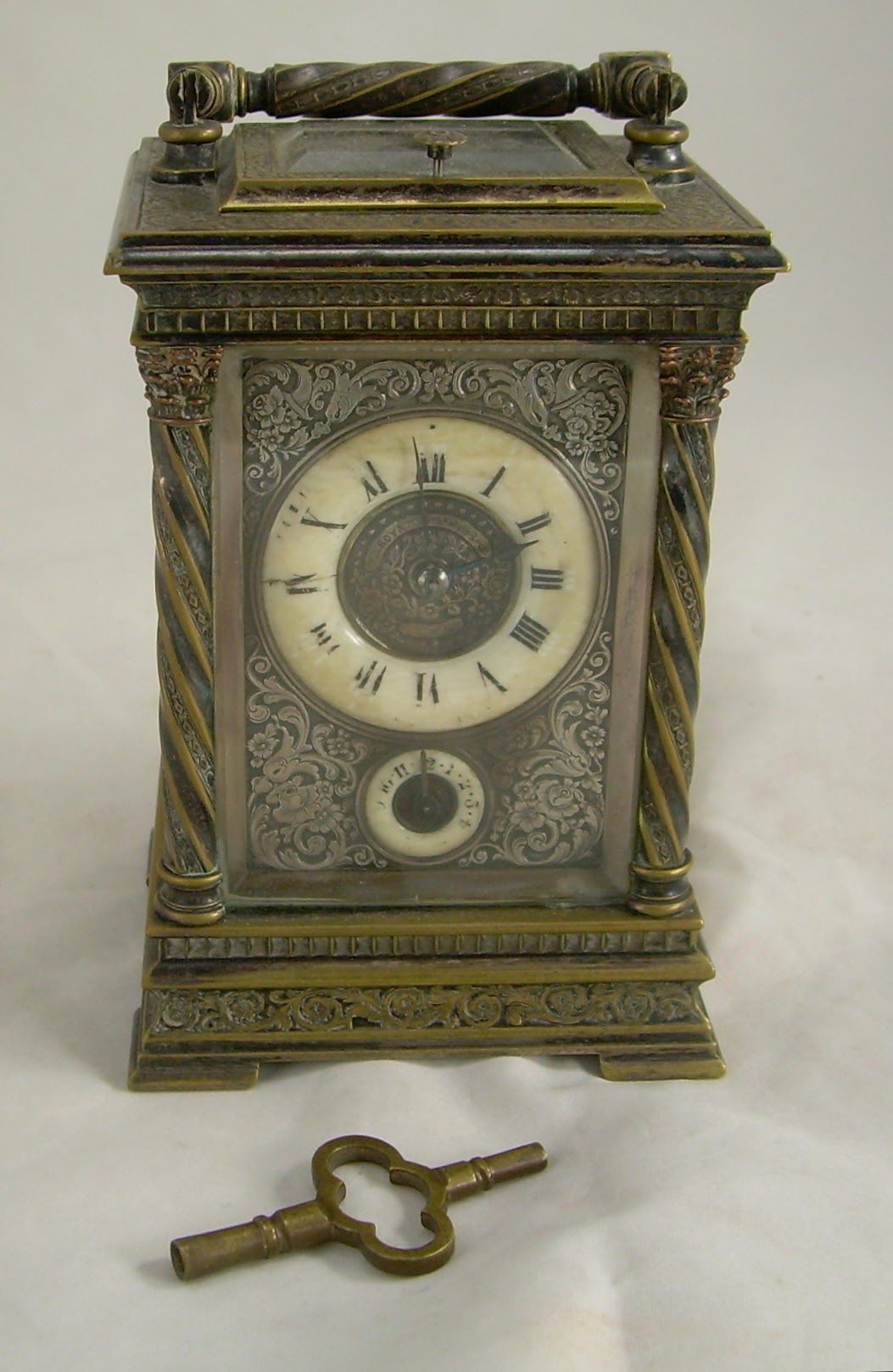 Antique brass mantel clock with a separate winding key on a white background