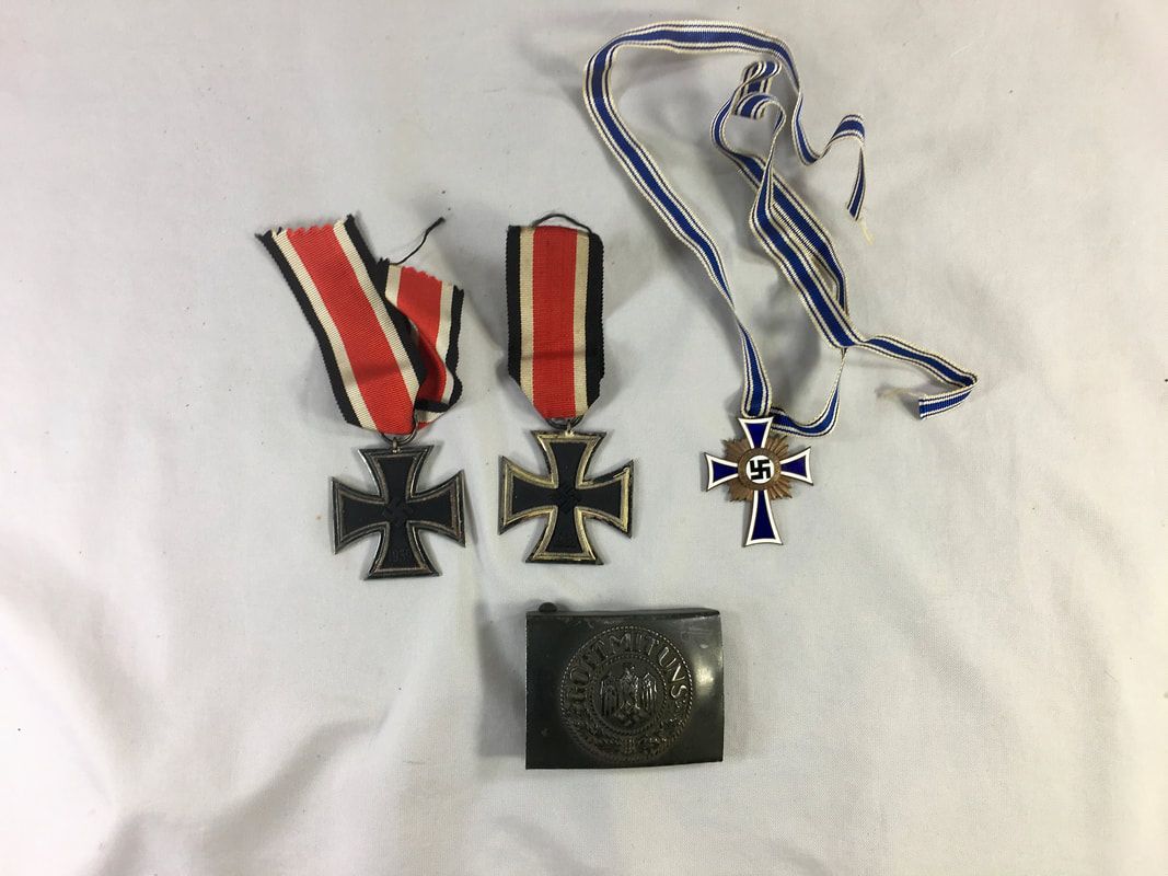 Three military medals with red-striped and blue ribbons and a dark metal badge on white background