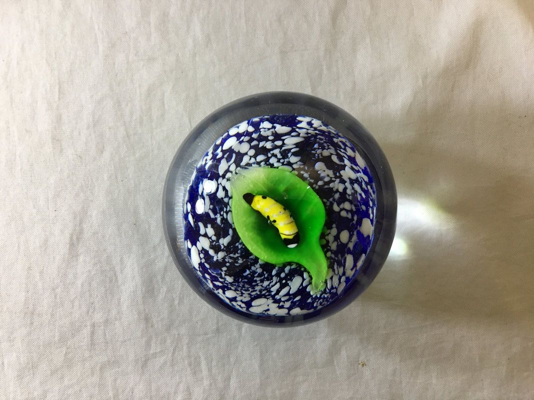 Blue and white patterned glass marble with a green center and yellow detail on a light surface