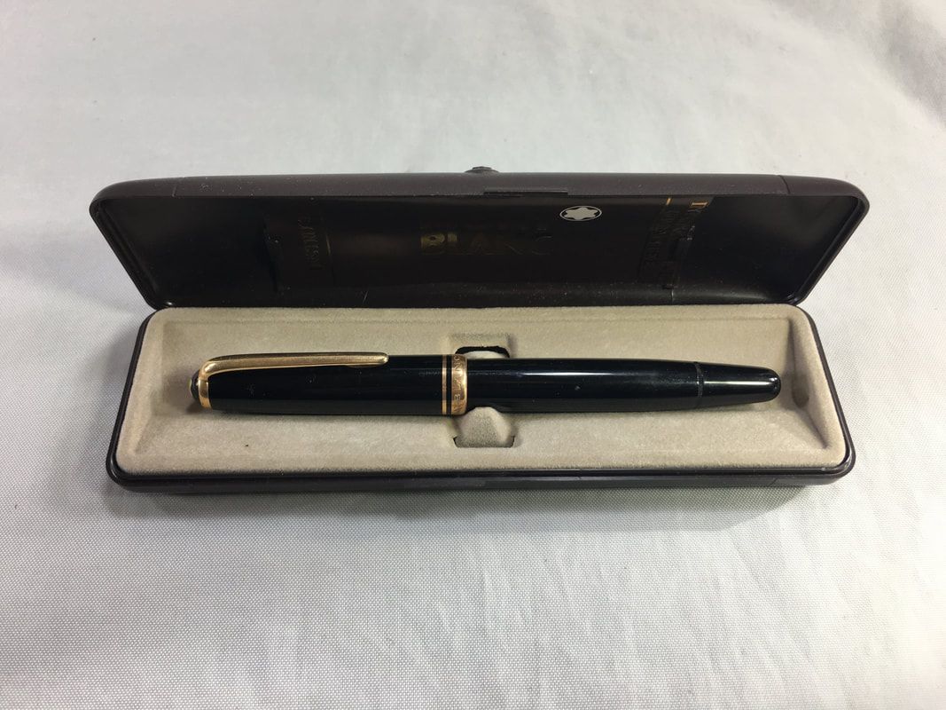 Black fountain pen in an open beige case on a white surface.