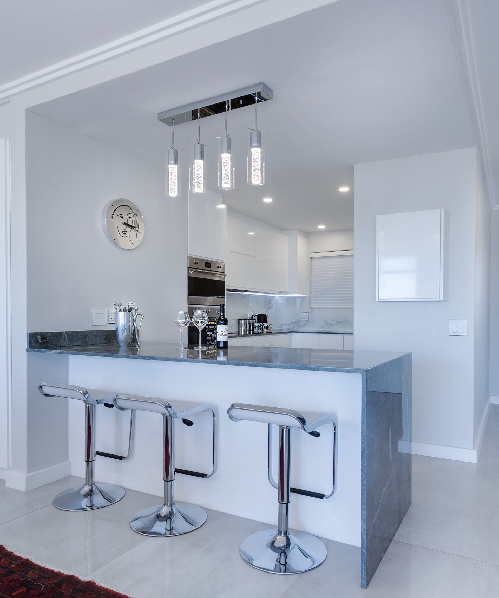 A kitchen with stools and a clock on the wall