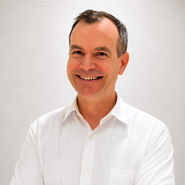 Smiling Zachary Stoughton in a white shirt against a light gray background