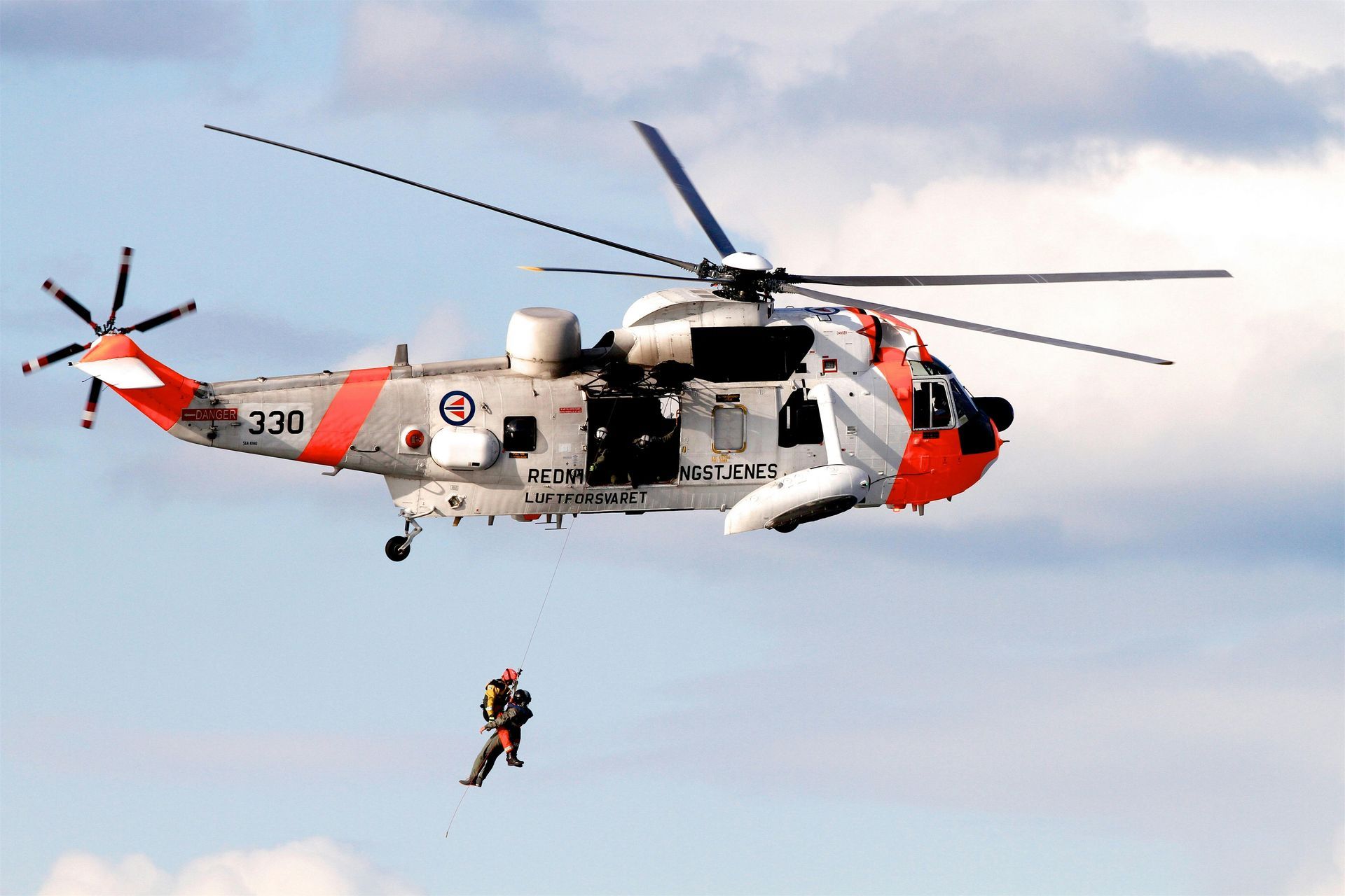 Un hombre está siendo rescatado por un helicóptero que tiene escrito 