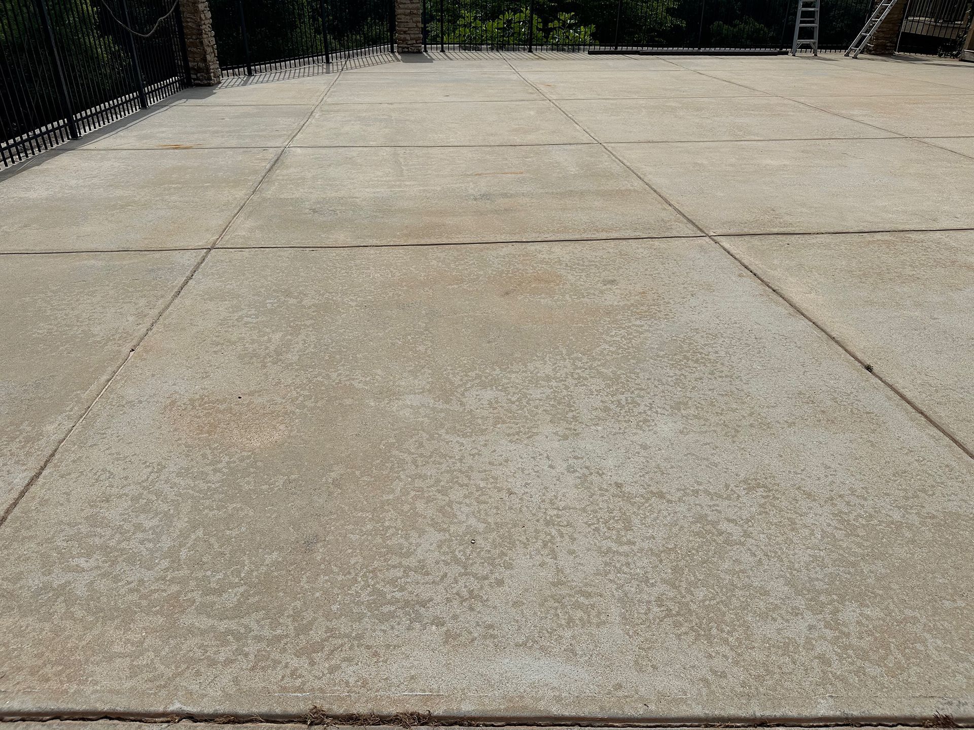 A large concrete driveway with a ladder in the background.