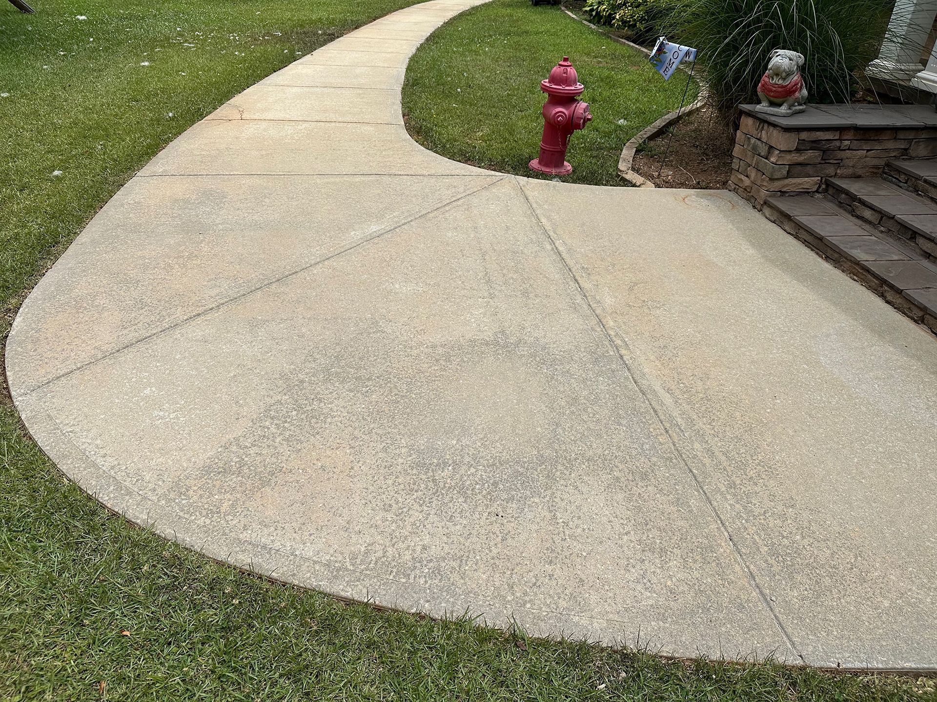 A concrete walkway with a red fire hydrant on the side of it.