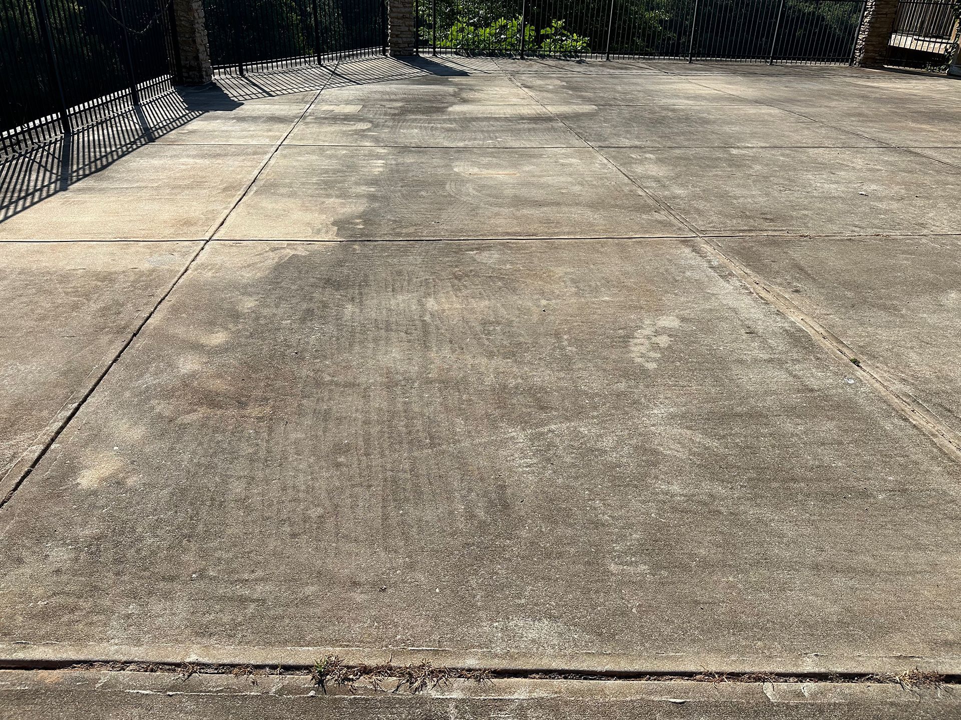A concrete driveway with a fence in the background.