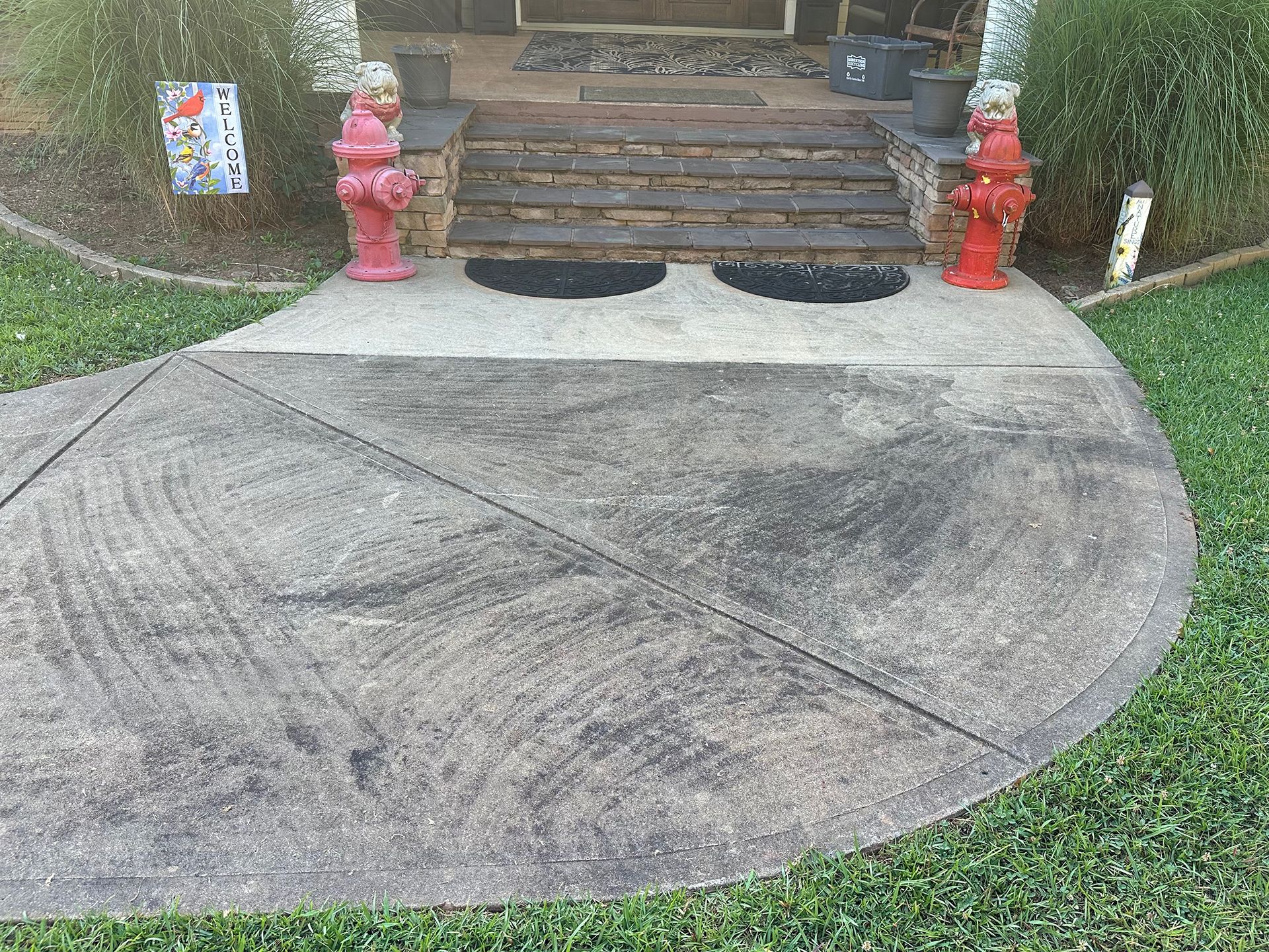 A concrete walkway with two red fire hydrants in front of a house.