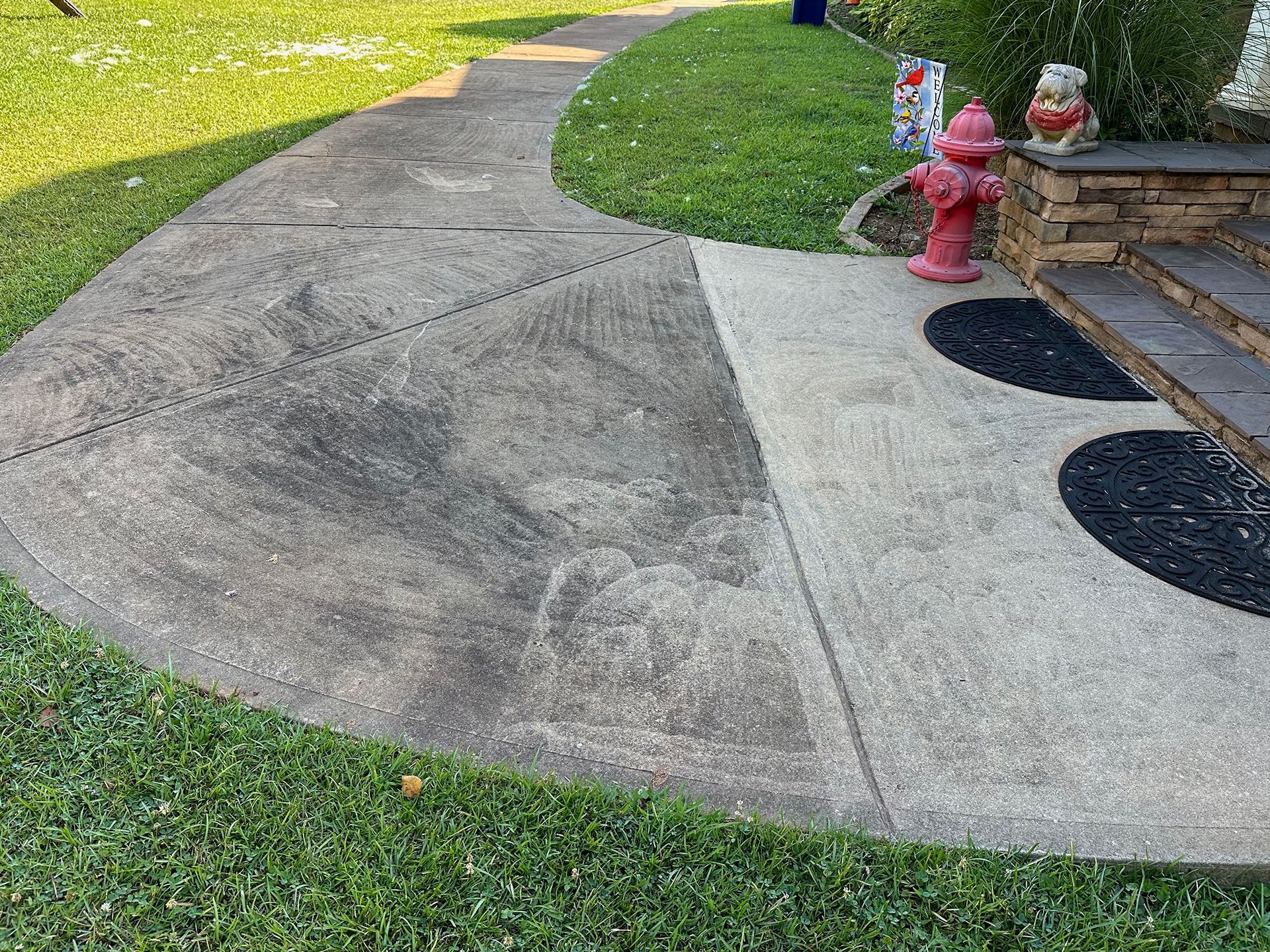 A concrete walkway with a red fire hydrant in the middle of it.